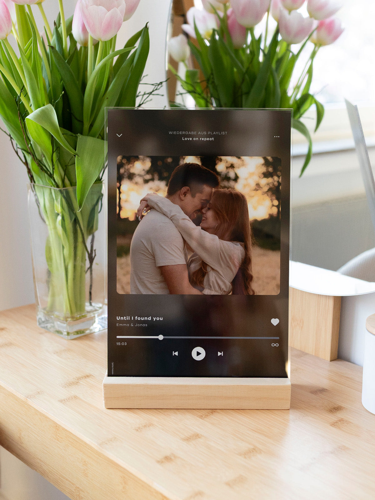 Personalisierter Acryl-Glas-Aufsteller mit Holzsockel, romantischem Paarfoto und individuellem Song – ideales Geschenk zur Hochzeit oder für den Jahrestag, stilvoll präsentiert mit Tulpen im Hintergrund.