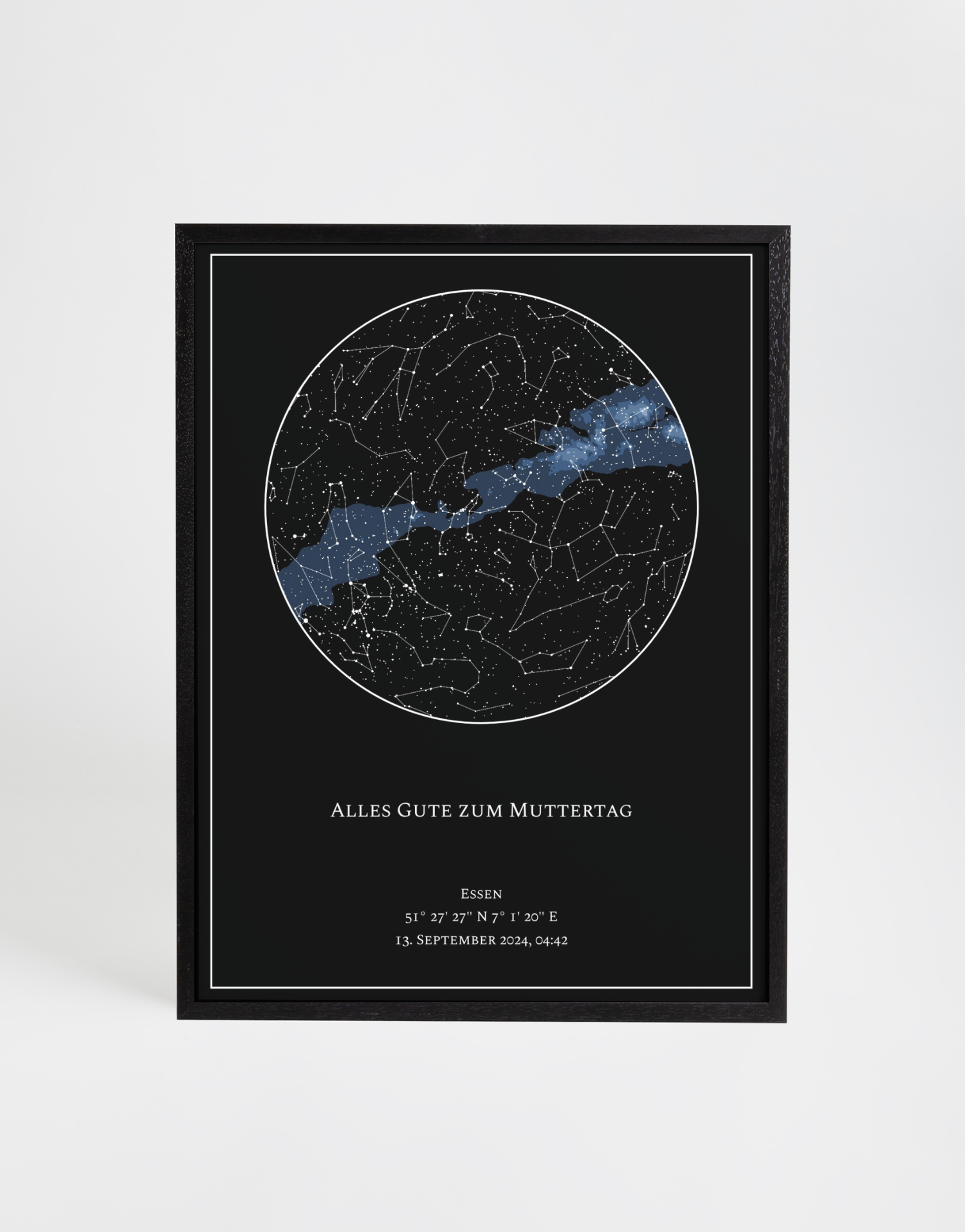 Schwarzes Poster mit runder, personalisierter Sternenkarte und auffälligem Milchstraßenband in Blau. Feine weiße Sternbilder stehen im Kontrast zum dunklen Hintergrund. Darunter ein individueller Text mit Datum und Koordinaten, eingefasst von einem schlichten weißen Rahmen. Eleganter schwarzer Holzrahmen umgibt das Design.